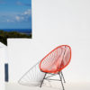 Original Acapulco Chair in der Farbe koralle vor weißer Wand