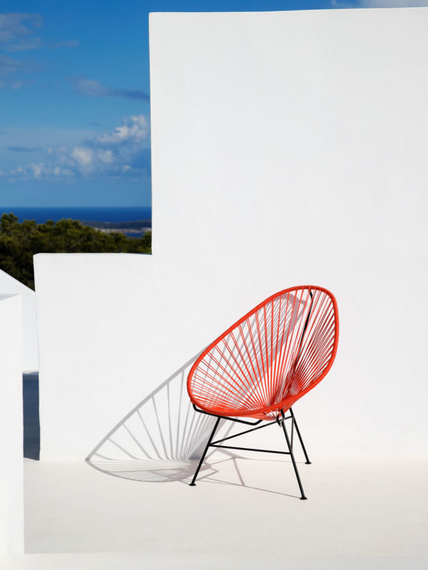 Original Acapulco Chair in der Farbe koralle vor weißer Wand