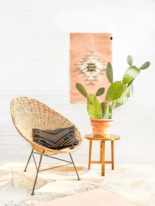 Original Acapulco Chair mit Palmenbezug und Kissen neben Kaktus