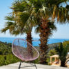 Original Acapulco Chair in der Farbe altrosa vor Palme und Meer