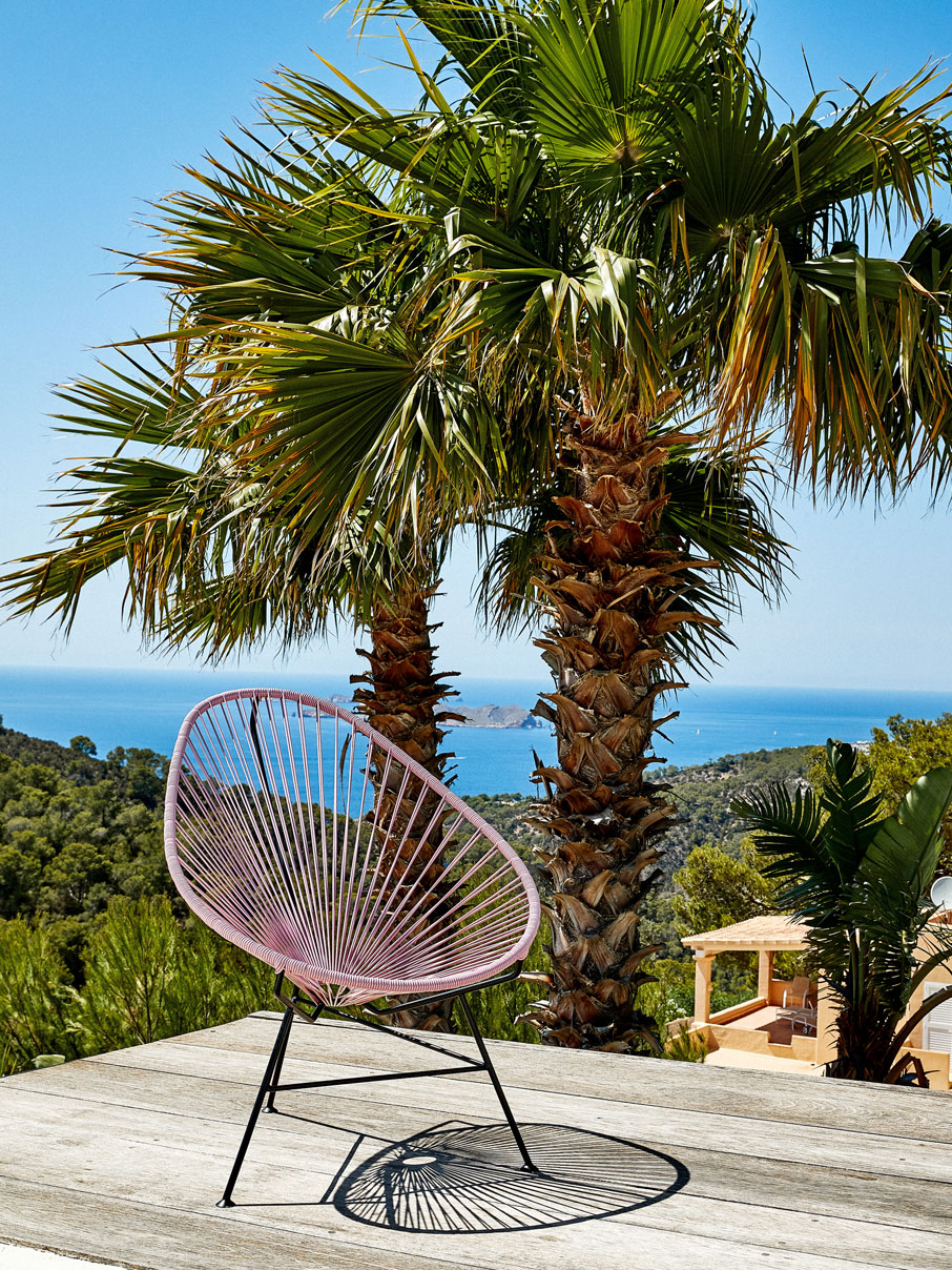 Original Acapulco Chair in der Farbe altrosa vor Palme und Meer