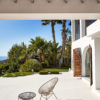 Original Acapulco Chair mit Beistelltisch beige auf Terrasse vor Palmen