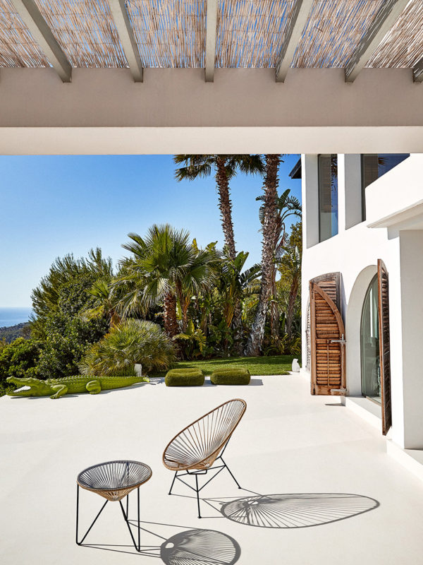 Original Acapulco Chair mit Beistelltisch beige auf Terrasse vor Palmen